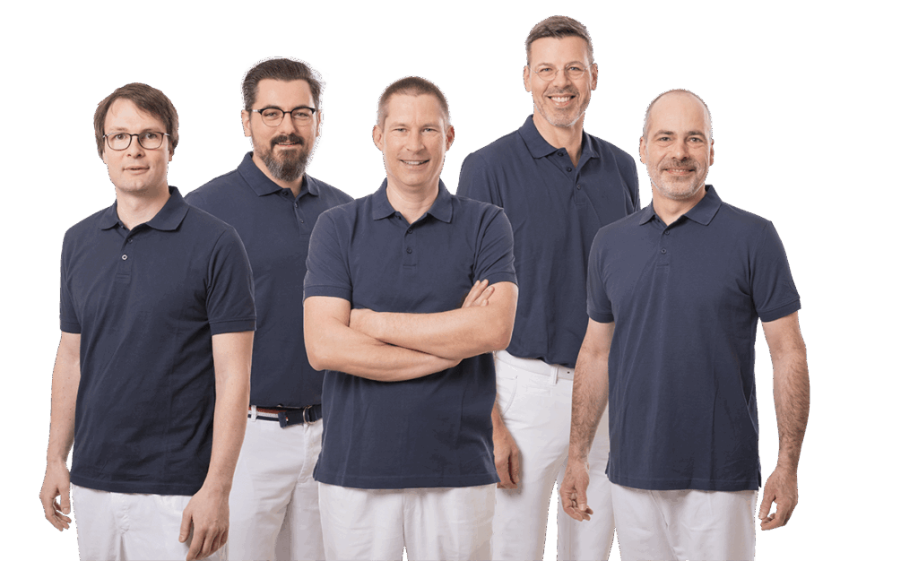 Fünf Ärzte in marineblauen Poloshirts und weißen Hosen stehen nebeneinander vor einem schlichten weißen Hintergrund, schauen in die Kamera und lächeln.